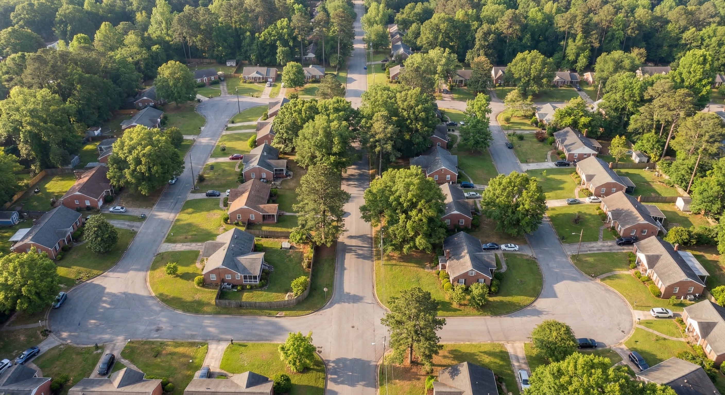 Aerial view of a residential neighborhood in Atlanta, Georgia, showing tree-lined streets and red-brick homes with green lawns in spring