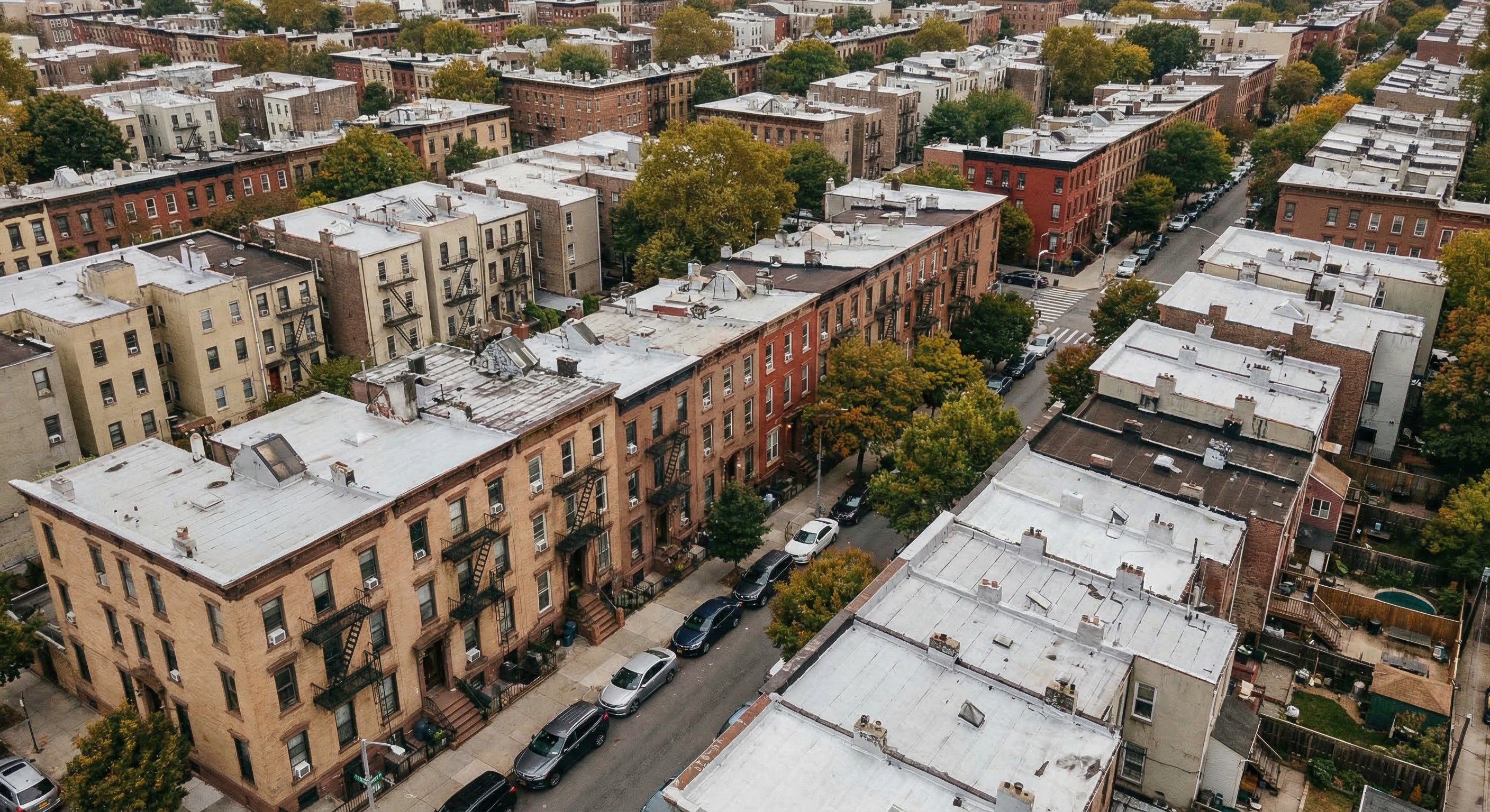 Aerial view of a dense New York City borough neighborhood with row houses and brownstones, showing urban residential density