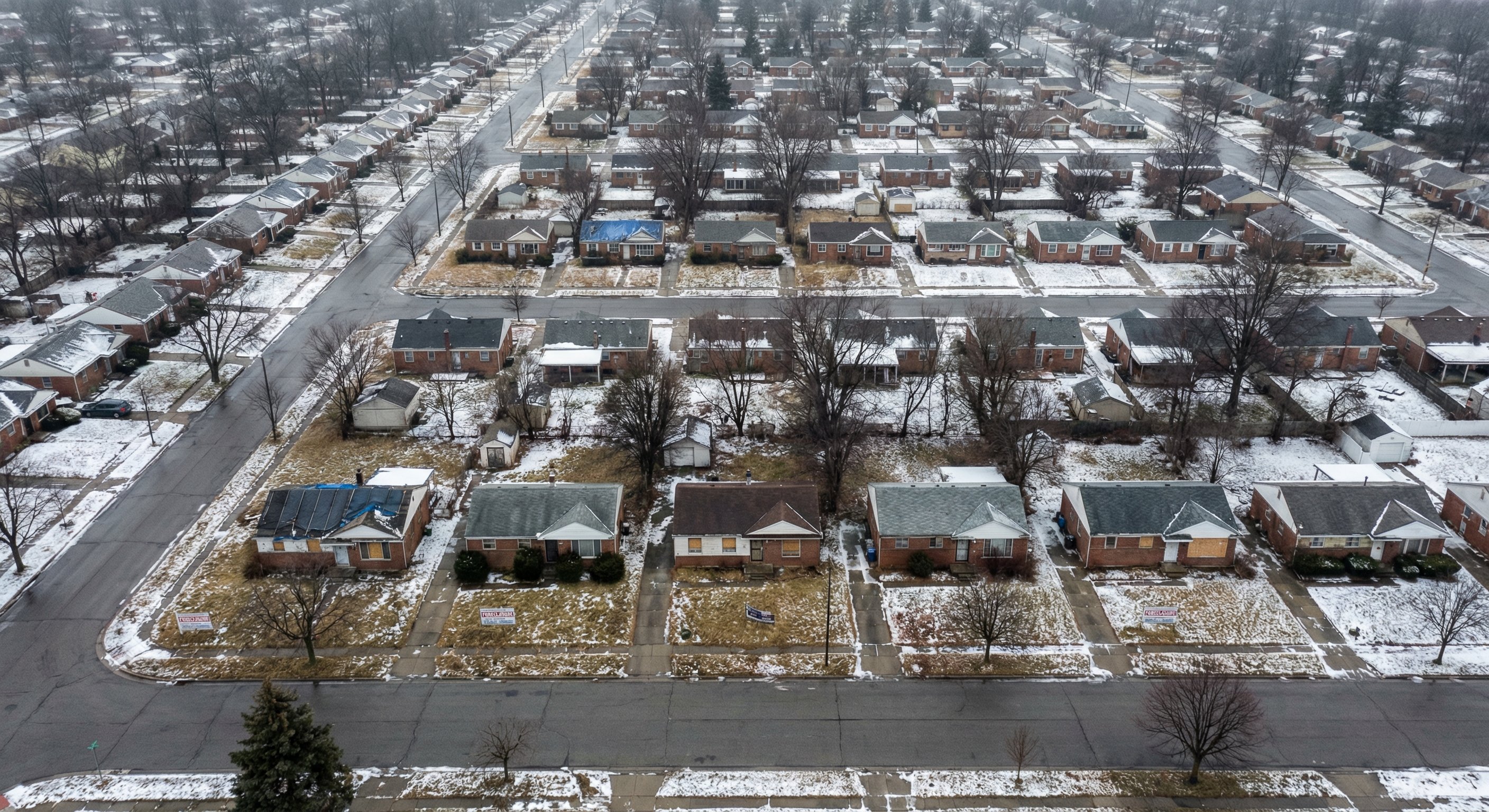 Aerial view of dense suburban Michigan neighborhood with some distressed properties visible among regular homes