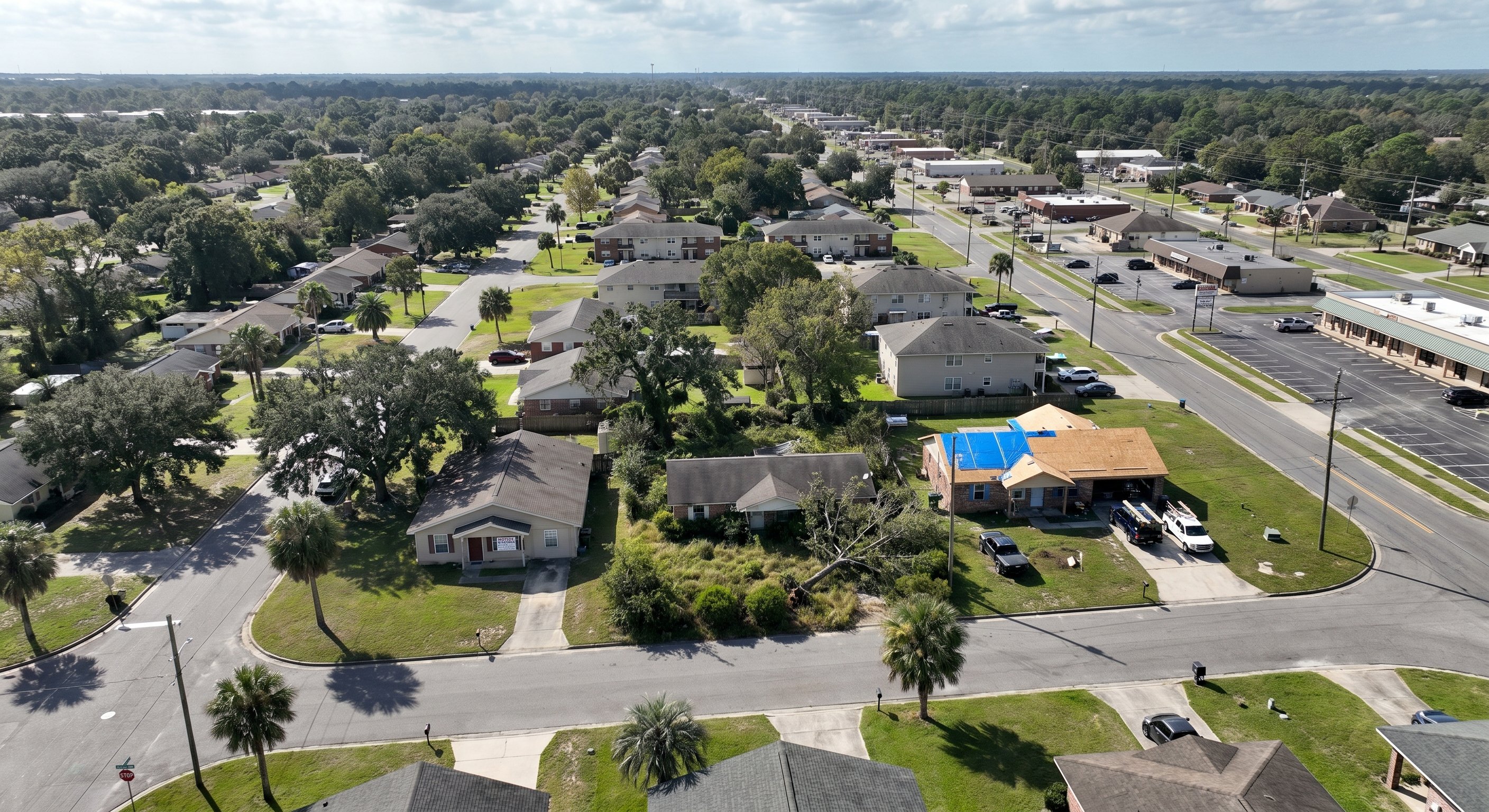 Aerial drone view of Mississippi Gulf Coast neighborhood with distressed properties and blue tarp on roof