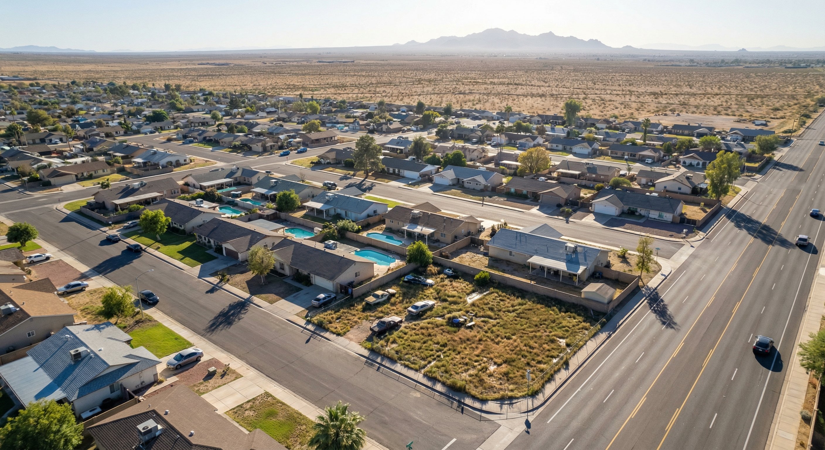 Aerial drone view of a suburban neighborhood with a mix of single-family homes, some with overgrown yards and deferred maintenance