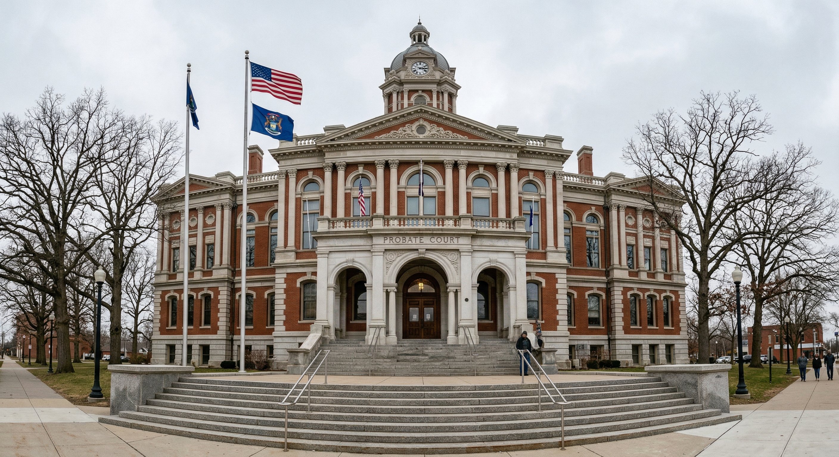 Michigan county courthouse exterior in classical architectural style, stone facade and broad steps, American flag and state flag flying, "Probate Court" signage visible, overcast afternoon light, wide-angle shot, documentary photography style