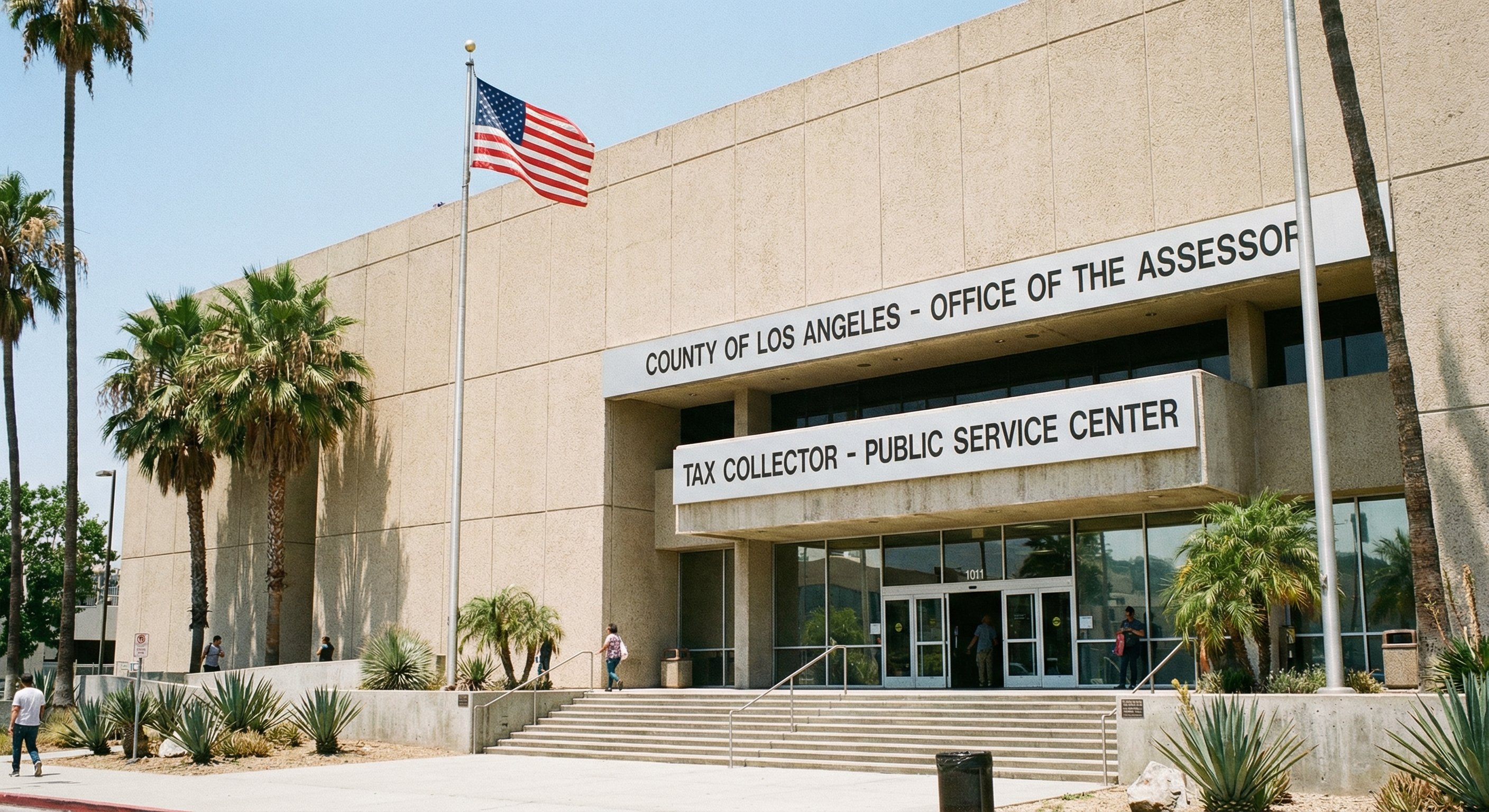 Exterior photograph of a California county tax assessor office, government building with "Tax Collector" signage, institutional facade, palm trees in foreground, bright California sunlight. Authentic government documentary photography, wide angle, natural light.