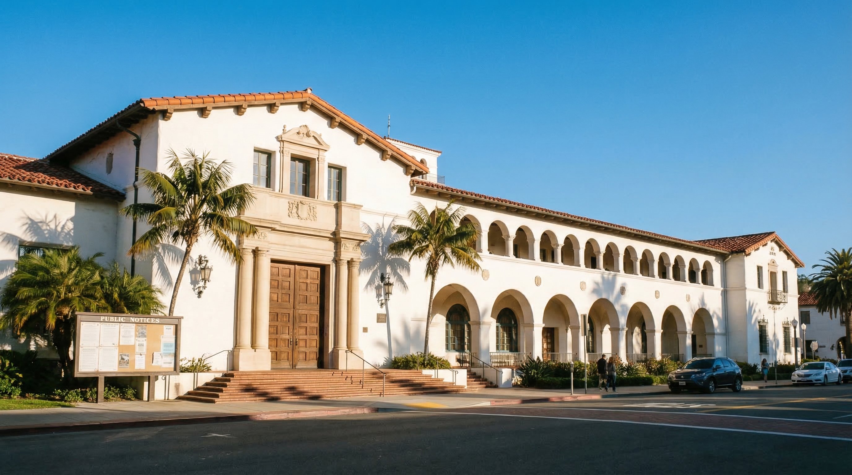 California county courthouse with Mission Revival architecture and palm trees under a clear blue sky, representing public records and property auction proceedings