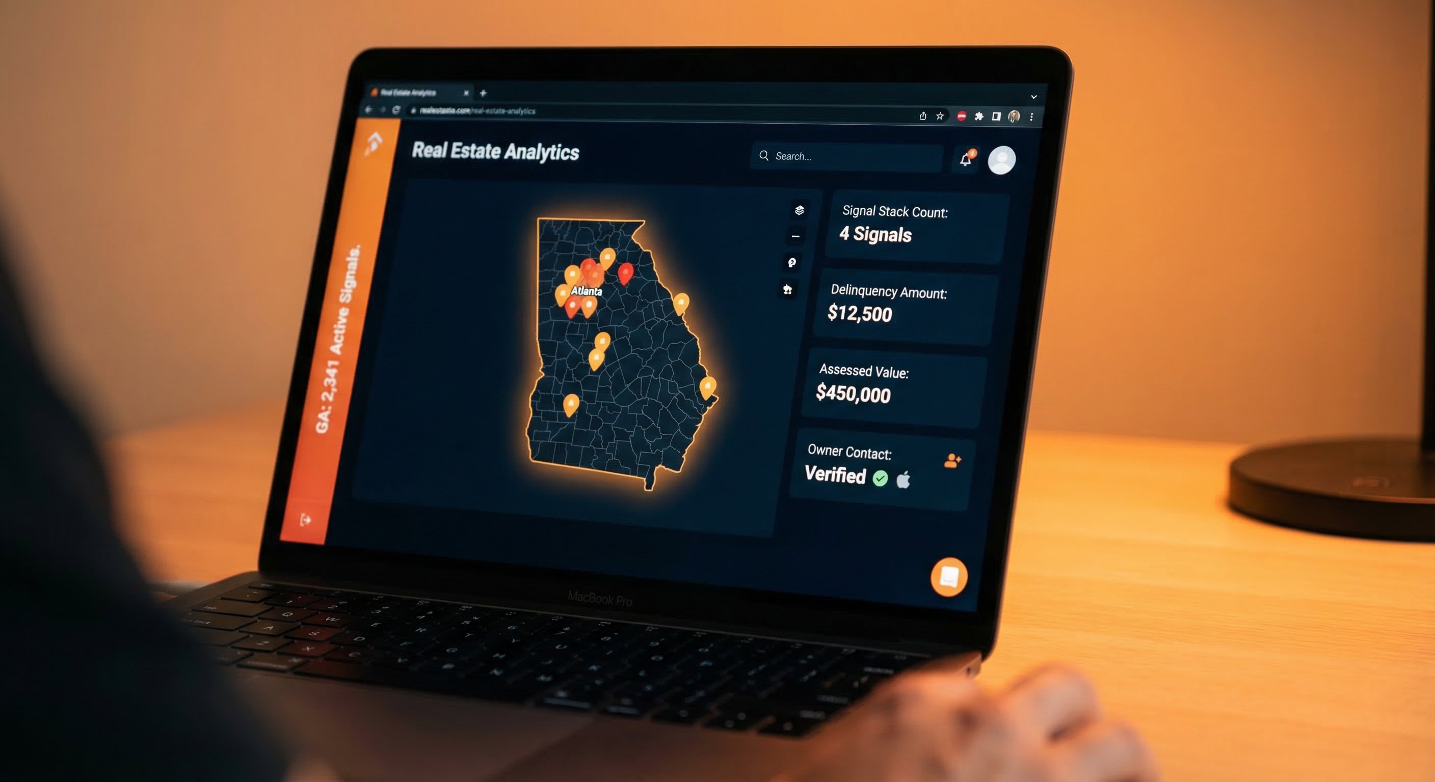 Modern laptop displaying a dark-themed real estate analytics dashboard with a Georgia property map, orange and red signal pins indicating distress concentrations, and data cards showing signal stacks per property