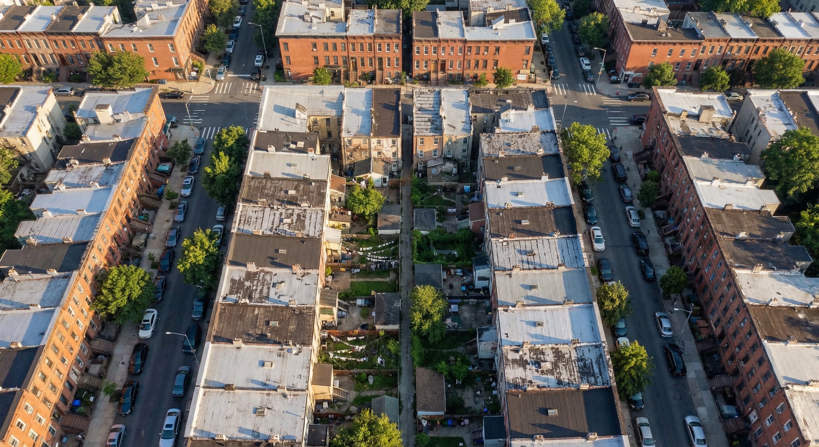 Aerial view of a dense Brooklyn New York neighborhood with rows of brick brownstone rowhouses, showing mixed property conditions for real estate investment research